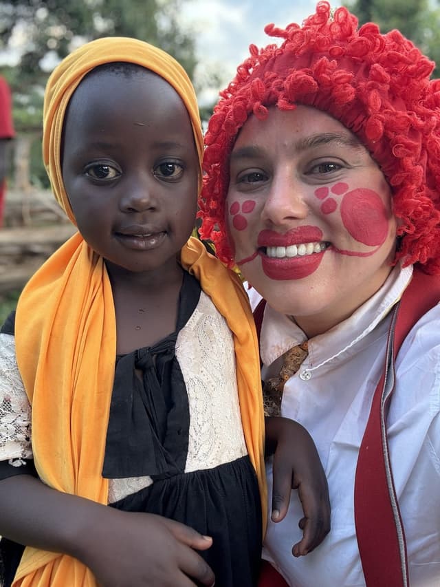 Feestclown in kostuum met kind in Uganda